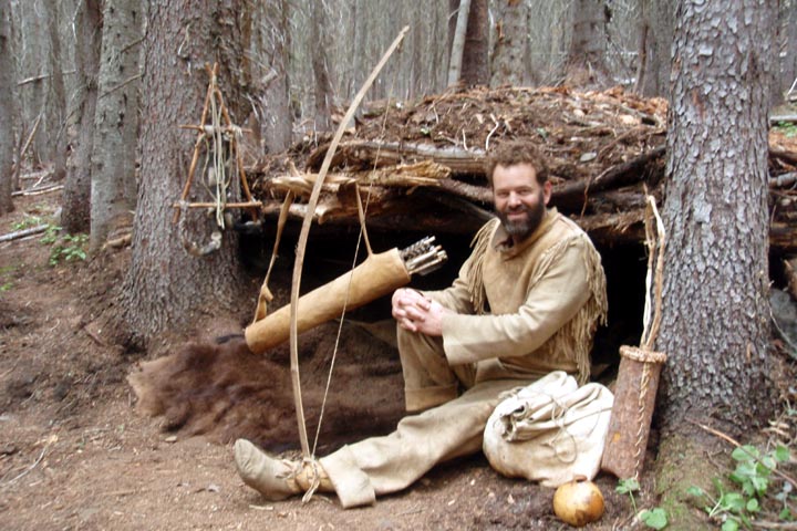 Author Tom Elpel in buckskins with a primitive shelter.