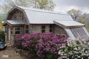 Slipform stone house with lilac hedge.